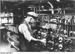 Pictured above is a Belgian worker who was forcibly taken from his home and made to work as a winder (someone who operates the bobbin) at the Siemens factory in Berlin, where enameled wires were manufactured. This photo, from August of 1943, was taken by order of Siemens and thus cannot be considered representative of actual working conditions in the factory. Source: Bundesarchiv, Bild 183-R46093 / CC-BY-SA, http://en.wikipedia.org/wiki/File:Bundesarchiv_Bild_183-R46093,_Belgischer_Zwangsarbeiter_bei_Siemens.jpg